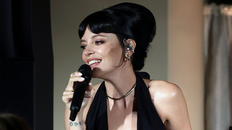 Lily Allen smiling and holding a microphone