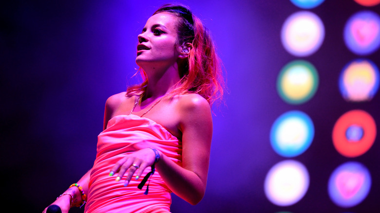 Lily Allen performing on stage in a pink dress.