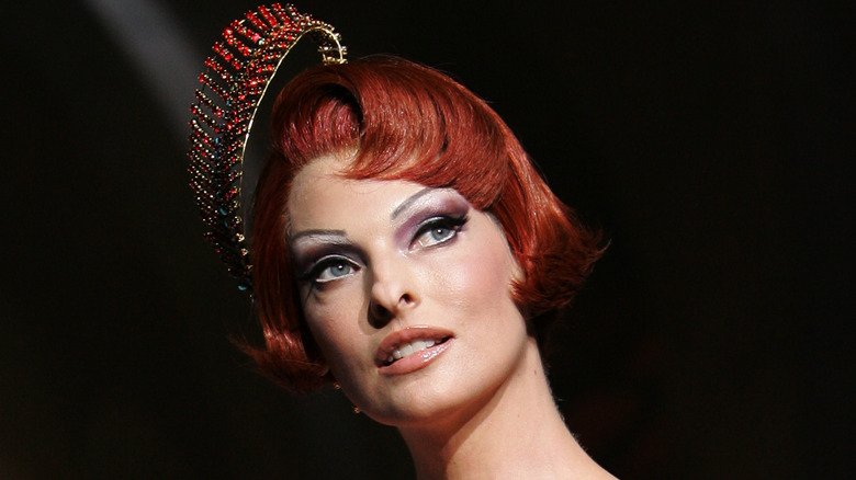 Linda Evangelista wearing a red fascinator