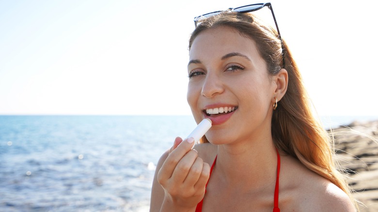 Woman applying lip balm on the beach