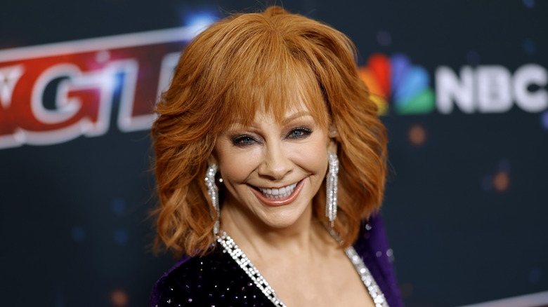 Reba McEntire smiling for photos in a glittery outfit