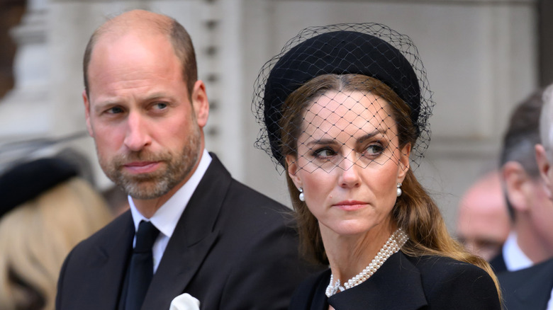 Kate Middleton and Prince William dressed in black looking downcast