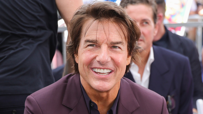 Tom Cruise in purple suit smiling.