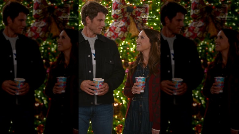 Screengrab from "Holiday Ever After: A Disney World Wish Come True" with a couple holding hot chocolate by Christmas lights
