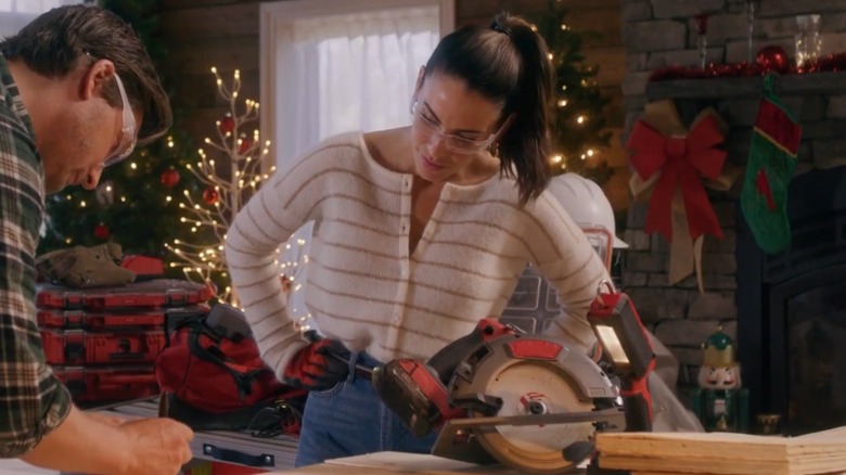 Jessica Lowndes wearing goggles by a table saw in "Christmas Under Construction"