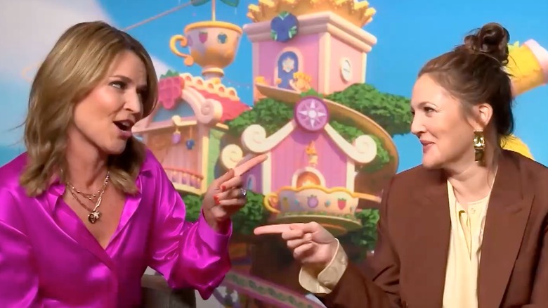 Savannah Guthrie and Drew Barrymore pointing at each other in an interview