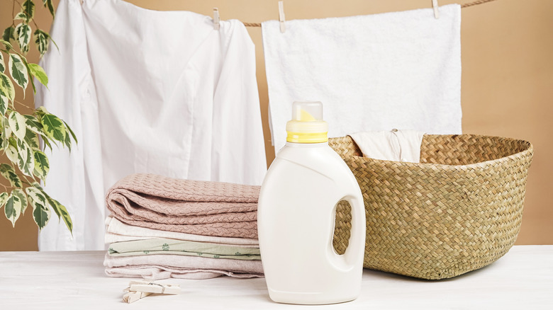 Hanging bedsheets next to folded towels, a basket and a detergent bottle