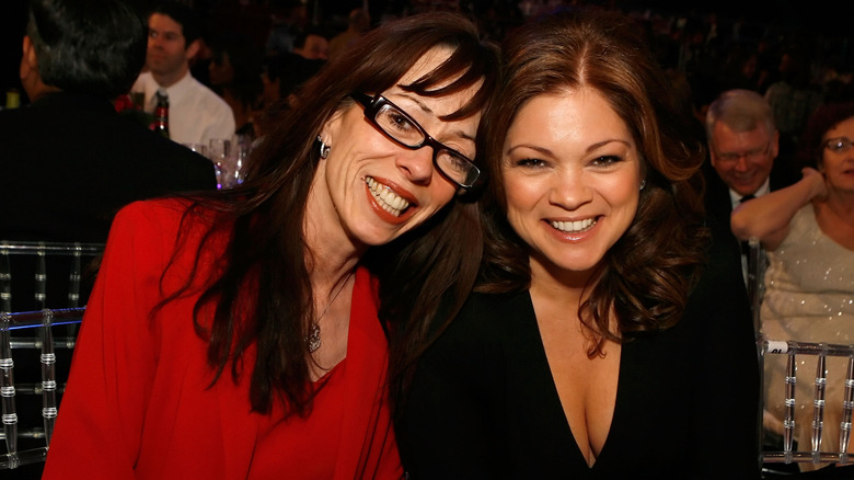 Mackenzie Phillips and Valerie Bertinelli with heads together at table