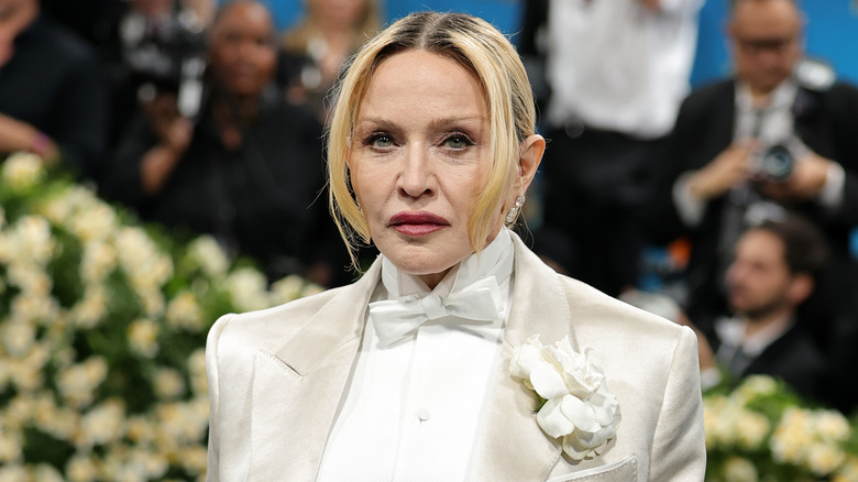 Madonna posing for photos in a white suit