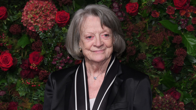 Maggie Smith in black suit against flower background