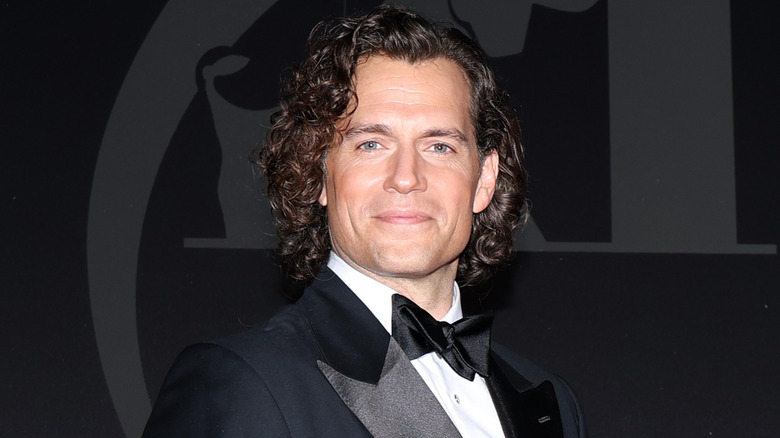 Henry Cavill with long curly hair in black formals and bowtie