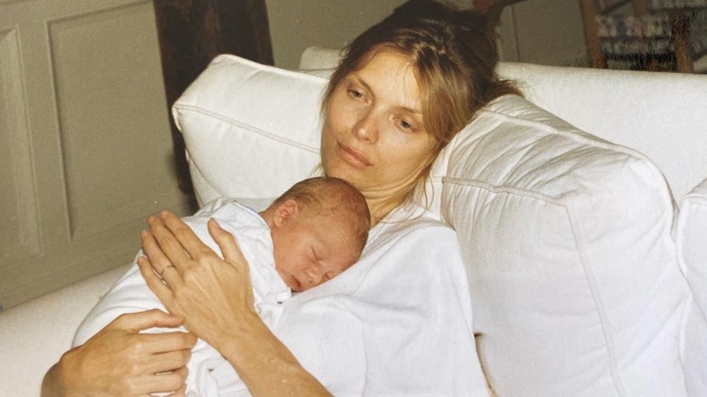 Michelle Pfeiffer looking thoughtful as she cuddles her baby