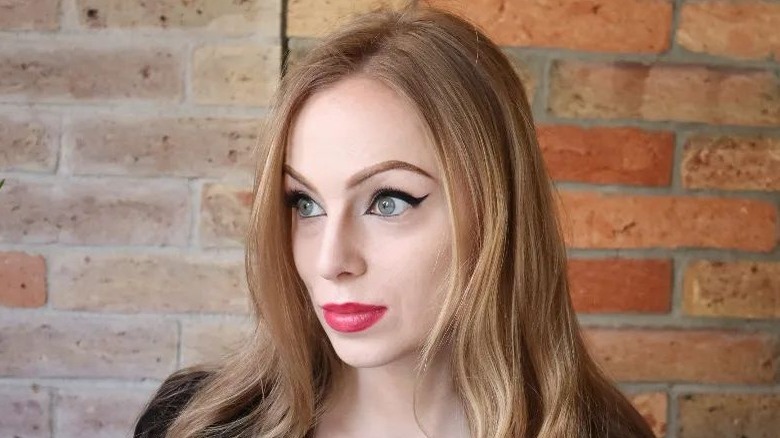 Woman with strawberry blonde hair and bright pink lipstick