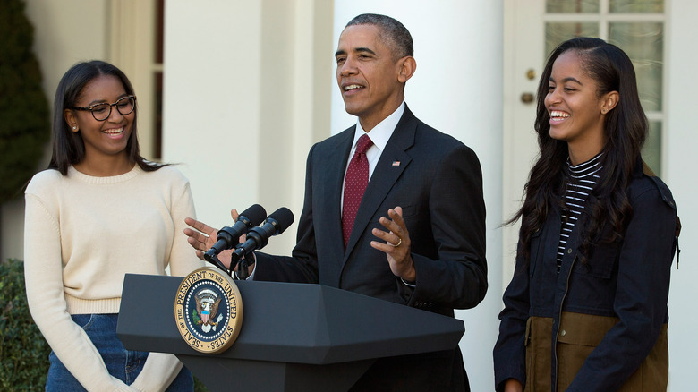 Malia and Sasha Obama smiling with Barack