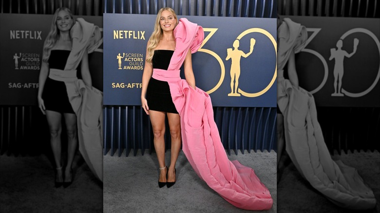 Margot Robbie at the Screen Actors Guild Awards in 2024 wearing a black cocktail dress with a large pink side sash
