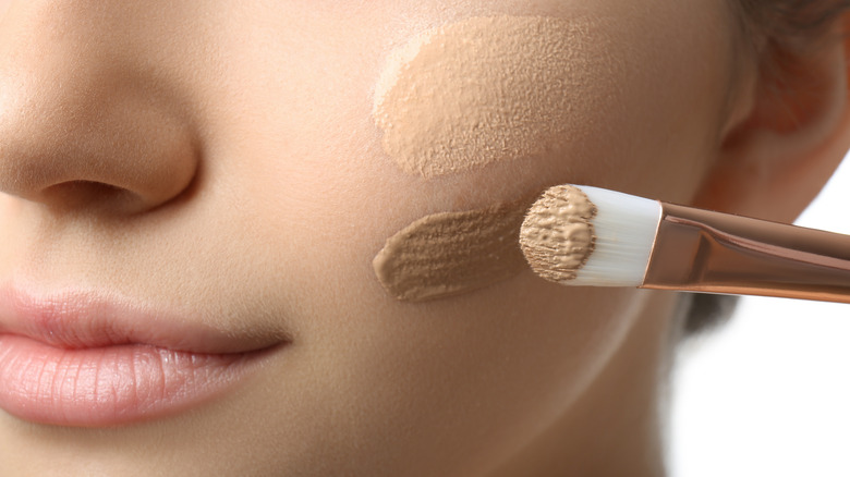 woman applying concealer to her skin