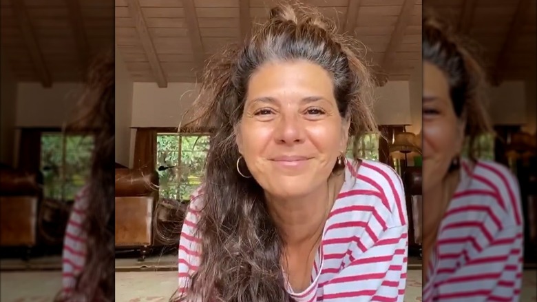 Marisa Tomei smiling and wearing a red and white striped shirt while doing yoga on the floor