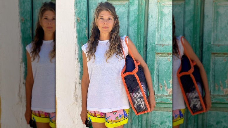 Marisa Tomei wearing a white T-shirt and sea life-print shorts and posing in front of a green door