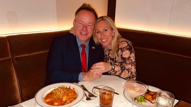 Brian Glenn and Marjorie Taylor Greene smile while showing off an engagement ring