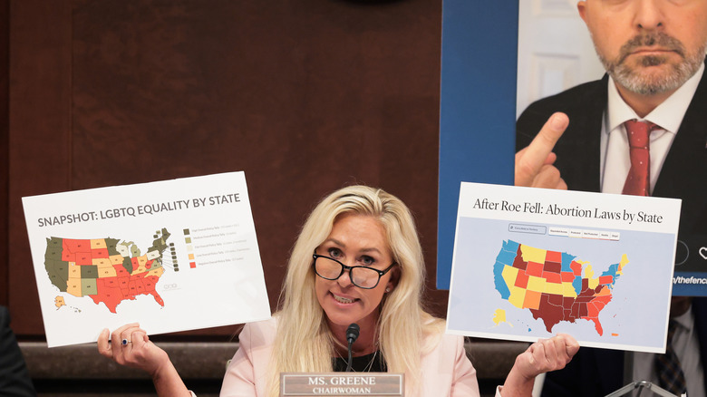 Marjorie Taylor Greene holding up maps of America during a House meeting