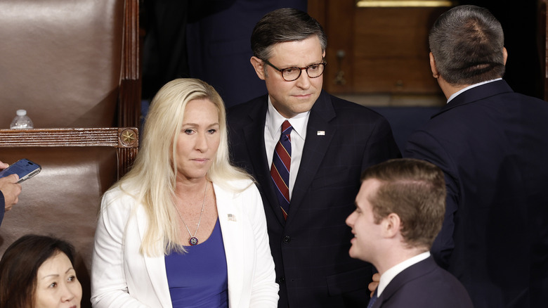 Mike Johnson standing behind Marjorie Taylor Greene in a suit