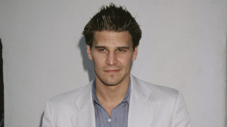 David Boreanaz posing in a white suit jacket with spiked hair.