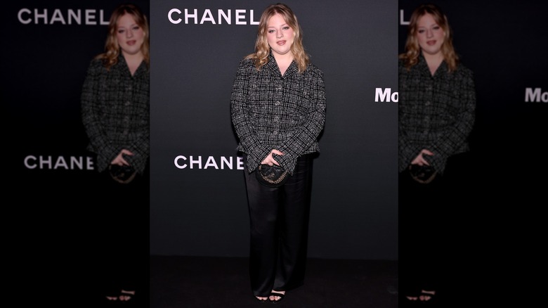 Francesca Scorsese at a Chanel red carpet in a black tweed top, slinky silk slacks, and strappy black sandals
