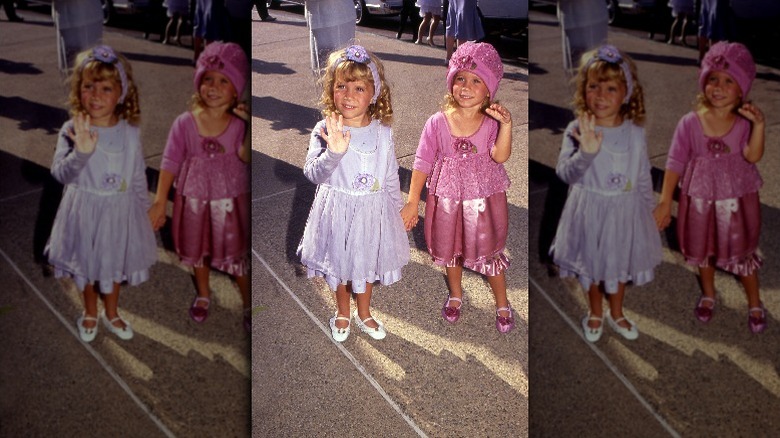 Mary Kate and Ashley Olsen as toddlers wearing pink and purple outfits
