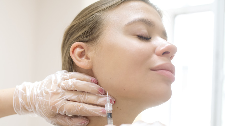 gloved hands giving woman jaw injection