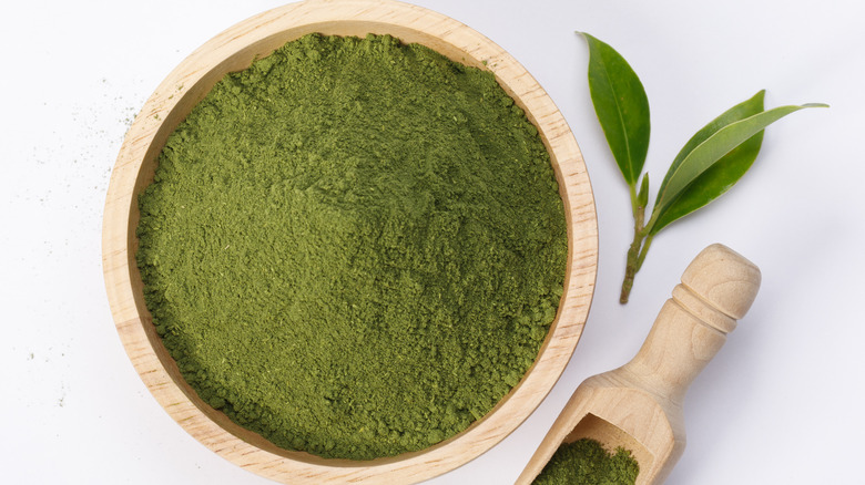 Green match powder in a wooden bowl against a white backdrop