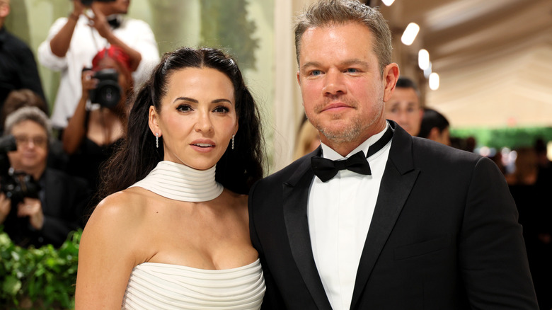 Luciana Barroso in a white gown with a choker and Matt Damon in a classic white tuxedo