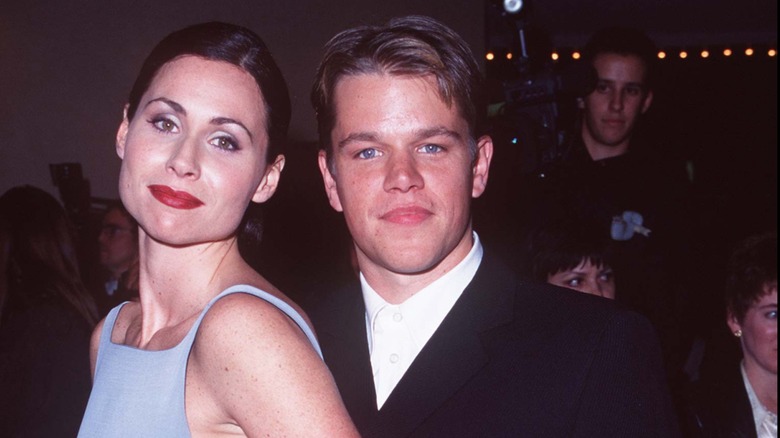 Minnie Driver in a blue dress posing with Matt Damon in a white shirt and black suit jacket.
