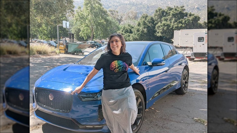 Mayim Bialik smiling in front of her Jaguar I-Pace in 2020