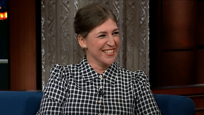 Mayim Bialik in a black and white checkered dress promoting her movie on The Late Show in 2022