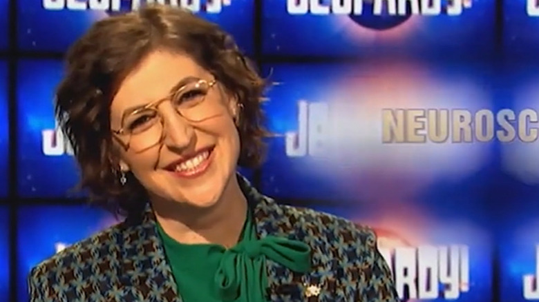 Mayim Bialik smiling while presenting Jeopardy!