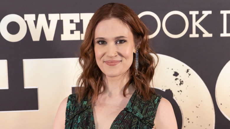 Smiling Paton Ashbrook wearing dangle earrings and wavy hair in 2023