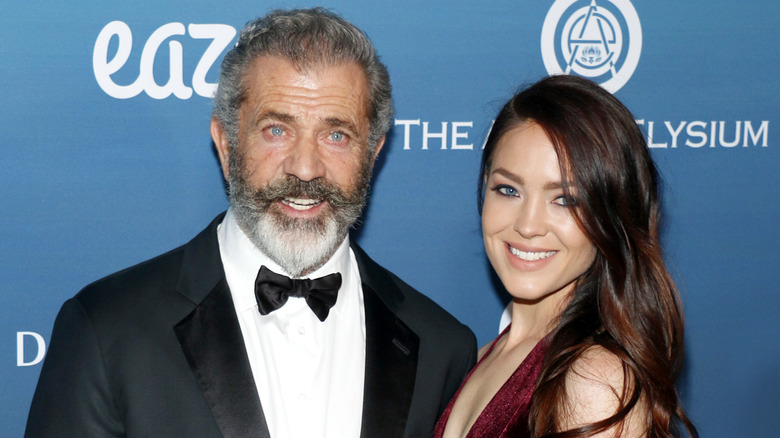 Mel Gibson and Rosalind Ross smile on step-and-repeat