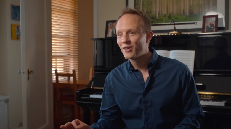 A smiling Aron Accurso sitting in front of a piano