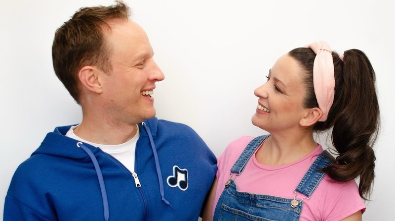 Aron Accurso and Ms. Rachel, him in blue and her in pink, smiling at each other