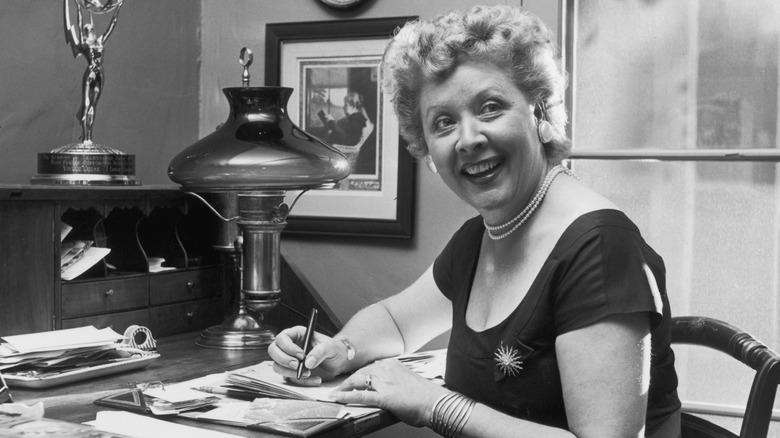 American actor Vivian Vance (1907 - 1979), best known as Ethel Mertz of television's 'I Love Lucy,' smiling and looking to the side as she writes letters at her home desk.