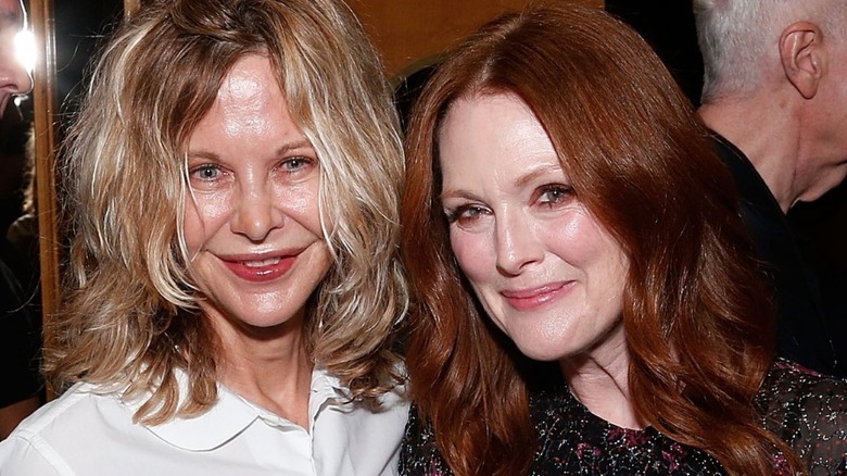 Meg Ryan smiling in a white collared shirt and black pants next to Julianne Moore who's wearing a black dress, while at The Academy of Motion Picture Arts and Sciences