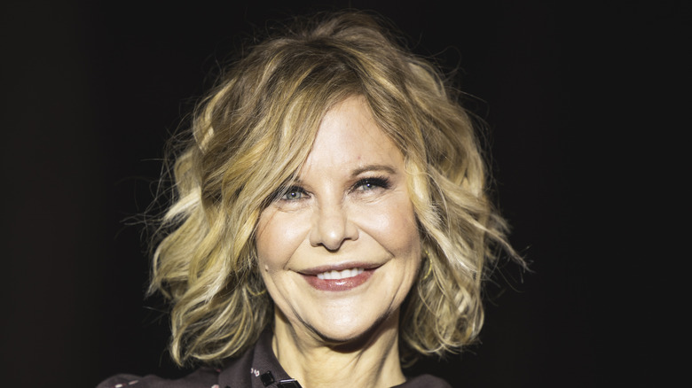 Meg Ryan smiling in a purple colalred shirt.