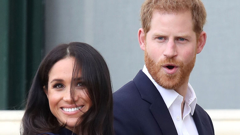 Meghan Markle smiles while Prince Harry looks shocked