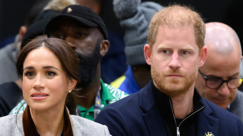 Meghan Markle and Prince Harry sitting at a basketball game.