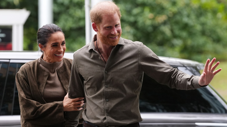 Prince Harry waving next to Meghan Markle