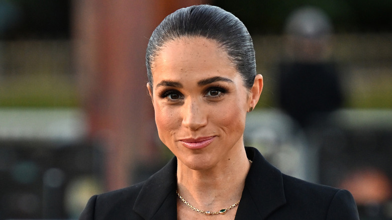 Meghan Markle in black suit with hair pulled back