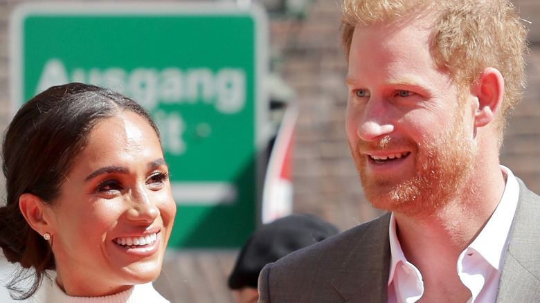 Meghan Markle (white halter top) smiles at Prince Harry