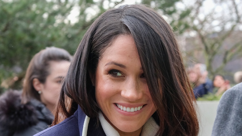 Meghan Markle smiling, looking sideways