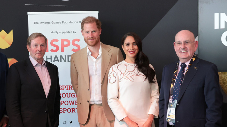 Prince Harry and Meghan Markle, Duke and Duchess of Sussex, surrounded by two men