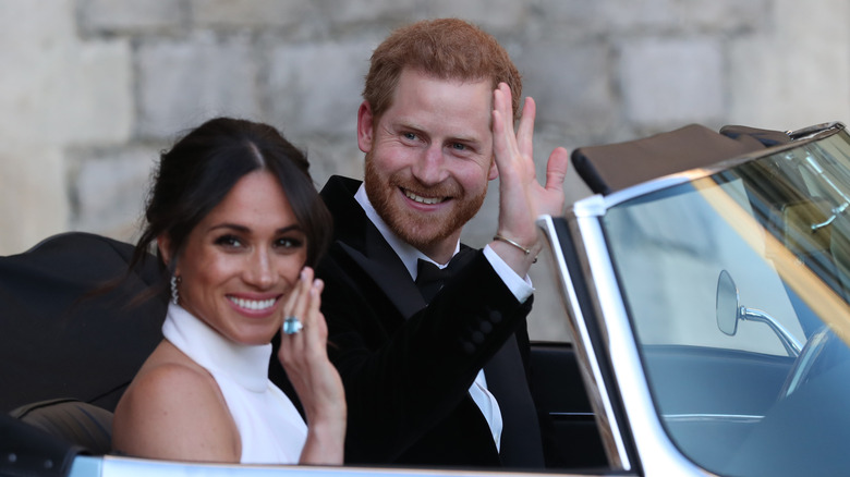 Prince Harry and Meghan Markle waiving from a car after their wedding ceremony